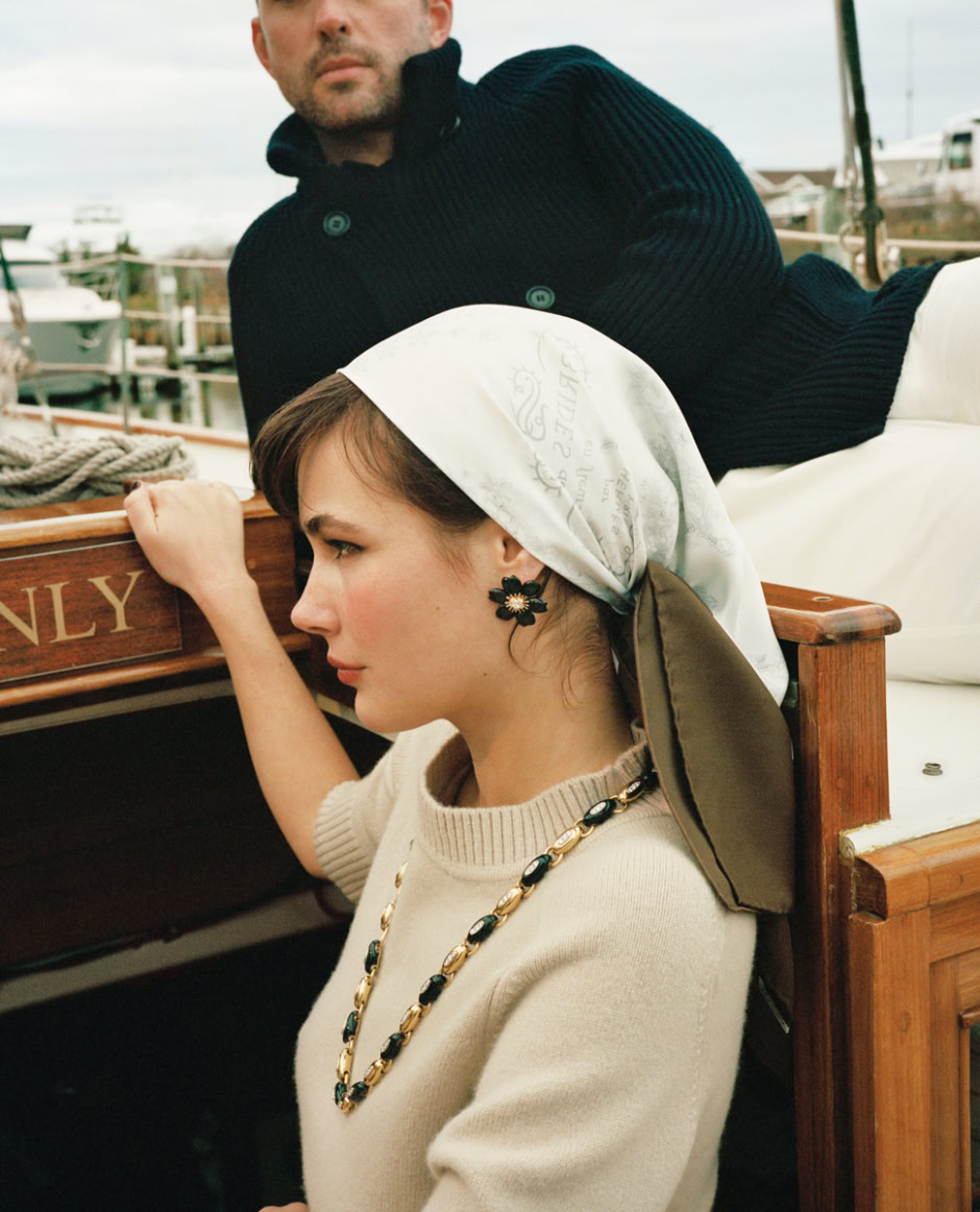 Navy coat and waterfall necklace on woman with vintage headscarf, dockside background of boats, yacht, luxury marina, ocean, leisure fashion, classic style, Pamela Hanson Photography.
