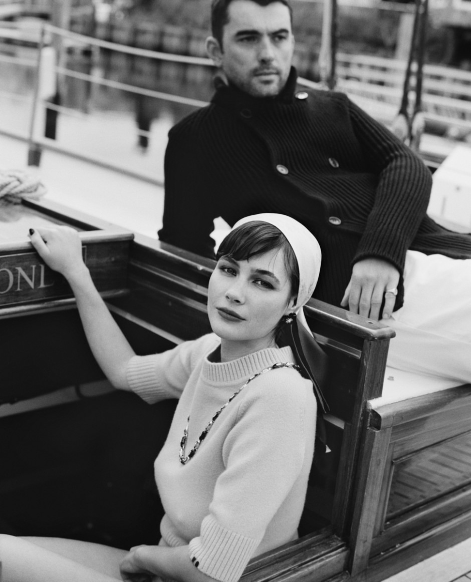 Black and white portrait of stylish man and woman on a wooden boat, fashion photography, elegant clothing, sophisticated mood, outdoor setting, monochrome photography, Pamela Hanson Photography.